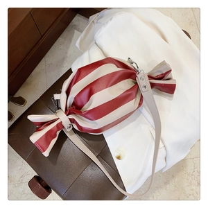 Gros plan du sac bandoulière en forme de bonbon avec rayures rouges et blanches et fermoir