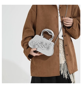 Detail of silver evening clutch with sparkling rhinestone leaf pattern and metal handle