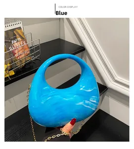 Detailed view of blue marble acrylic clutch with round handle and gold chain strap