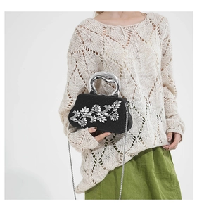 Detail of black rhinestone dinner bag with crystal floral pattern and metal handle
