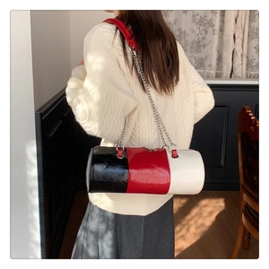 Détail du sac cylindre bicolore montrant le cuir verni brillant et la bandoulière chaîne