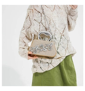 Detail of champagne gold evening bag with rhinestone flowers and silver handle