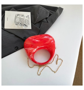 Detail of red marble acrylic crescent bag with golden chain and round hollow handle