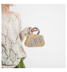 Close-up of champagne gold evening bag with floral diamond patterns and metal handle