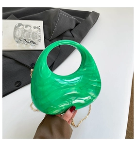 Detail of green marble acrylic moon bag with golden chain and sleek crescent structure