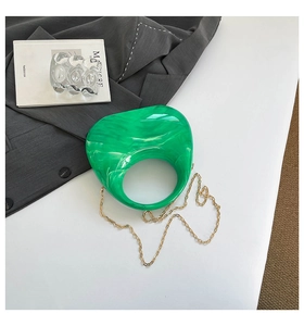 Detailed texture of green marble acrylic moon bag with a gold chain strap on a blazer