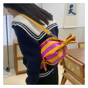 Mannequin portant un sac à bandoulière plissé en forme de bonbon rayé jaune et violet