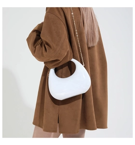 Close-up of white crescent shoulder bag with glossy finish and gold metal chain strap