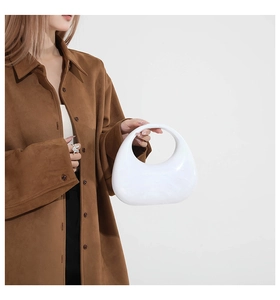 Close-up of minimalist white acrylic half-moon bag with integrated round handle design