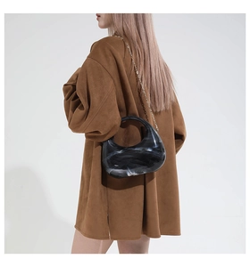 Acrylic marble crescent bag with chain strap held by model wearing brown coat