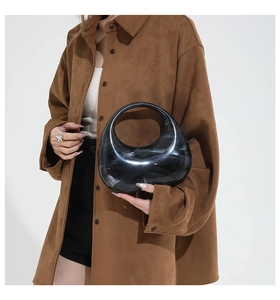 Close-up of black marble acrylic half-moon clutch bag held by a model with chain detail