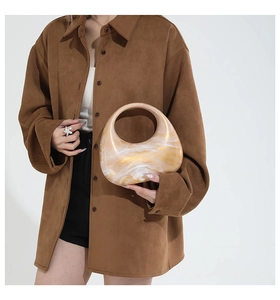 Chic acrylic half-moon bag with marble texture held by a model in a brown suede shirt