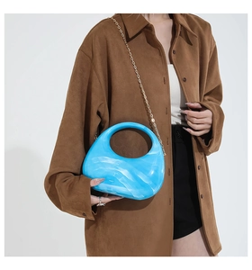 Detail of royal blue marble acrylic crescent bag with golden chain on a model