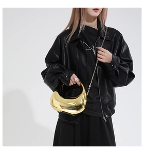 Close-up of polished gold crescent evening bag with sleek mirror finish and chain strap
