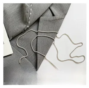 Detail of silver chain strap and sparkling rhinestones on the gold evening box bag