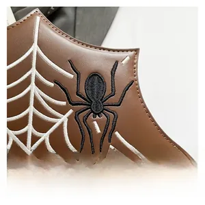 Macro detail of high-quality brown faux leather with white spider web and spider embroidery