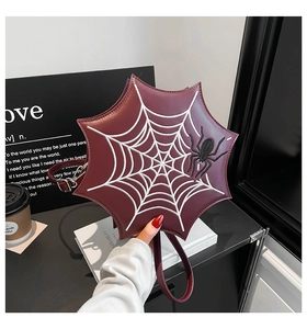 Detail of burgundy spider web shaped handbag featuring white stitching and spider embroidery