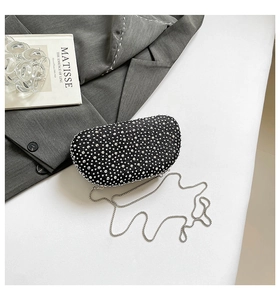 Detail of a semi-circular black evening clutch with sparkling rhinestones and silver chain