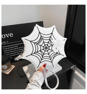 Detail of white spiderweb shaped handbag with black embroidery and 3D spider accent
