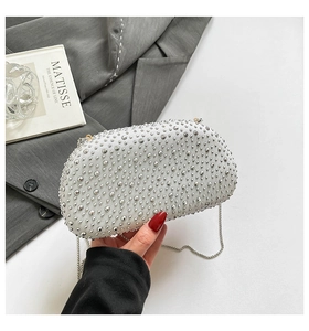 Silver semi-circle evening bag with studs and metal chain strap shown with fashion decor