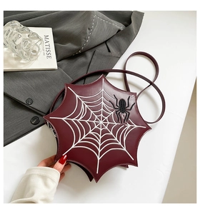 Detail of burgundy spider web crossbody bag with white stitching and spider embroidery