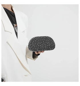 Detail of a black evening clutch bag encrusted with silver rhinestones held by a model