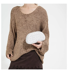 Close-up of white crystal rhinestones on an oval evening clutch with metal chain detail