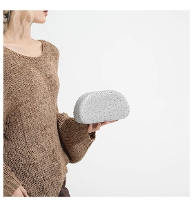 Close-up of a silver glitter evening clutch bag with sequins held by a model in a knit sweater