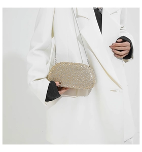 Detail of champagne gold evening bag with rhinestones and metal chain strap on model