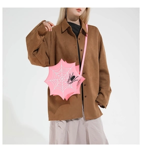 Pink spiderweb shaped crossbody bag with black 3D spider detail shown on a female model