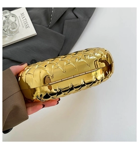 Macro detail of glossy gold metal woven texture on oval clutch bag with elegant finish