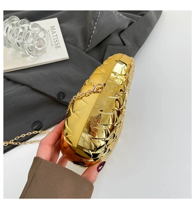 Macro shot of gold quilted leaf-shaped evening clutch bag with delicate metal chain detail