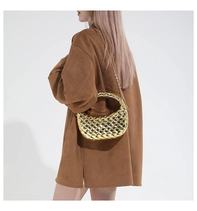 Détail d'un sac hobo doré tissé métallique avec bandoulière chaîne porté sur une veste brune