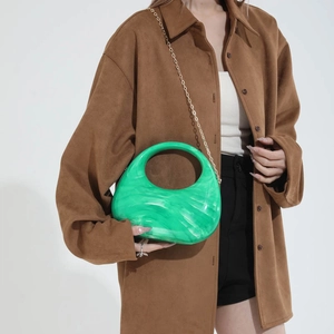 Green marble acrylic crescent handbag with gold chain strap shown on a model