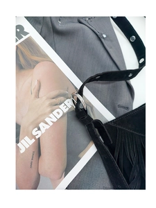 Close-up of black suede crossbody bag with fringe tassel detail and silver round buckle
