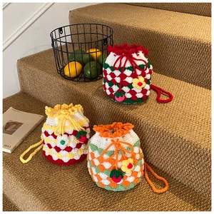 Three handmade crochet bucket bags with checkerboard patterns and strawberry charms