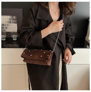 Detail of dark brown suede shoulder bag with silver rivets and metal chain strap