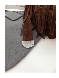 Detail of silver heart-shaped hardware and brown suede texture on a tassel shoulder bag