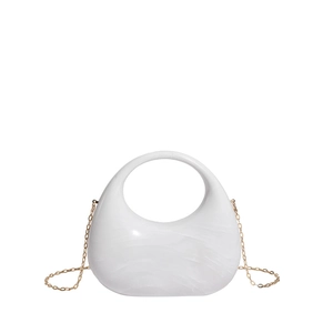 Macro view of semi-circular acrylic handbag with white marble texture and gold chain