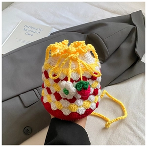 Detailed macro of handmade crochet bucket bag with strawberry and flower charms