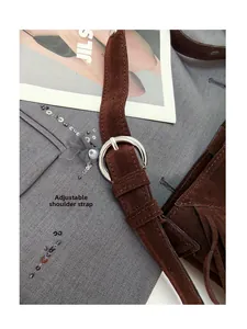 Detail of adjustable shoulder strap with silver buckle on brown suede tassel bucket bag