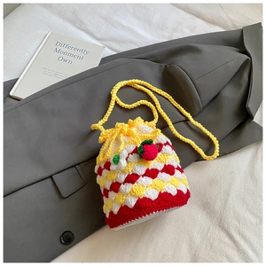 Detail of handmade crochet strawberry bucket bag with colorful knit pattern and shoulder strap