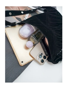 Detail view of the black suede bucket bag showing its spacious interior and long tassels