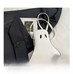 Ghost-shaped mini crossbody bag shown next to a smartphone for size scale comparison