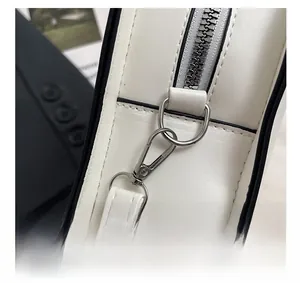 Macro detail of the silver metal hook and zipper on a white leather ghost handbag
