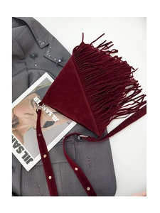Macro shot of burgundy suede triangular bag detailing with long fringe and metal rivets