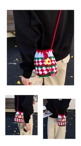 Detail of handmade crochet bucket bag featuring colorful checkered knit and floral charm