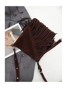 Close-up of vintage brown suede crossbody bucket bag featuring long fringe and adjustable strap