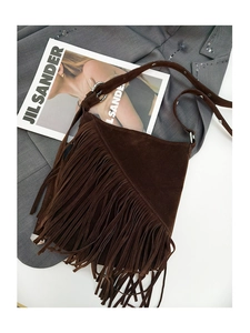 Detail of brown suede tassel crossbody bag with silver hardware on a grey sequined blazer
