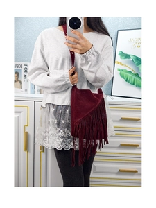 Detail of burgundy suede crossbody bag with long fringes and adjustable strap